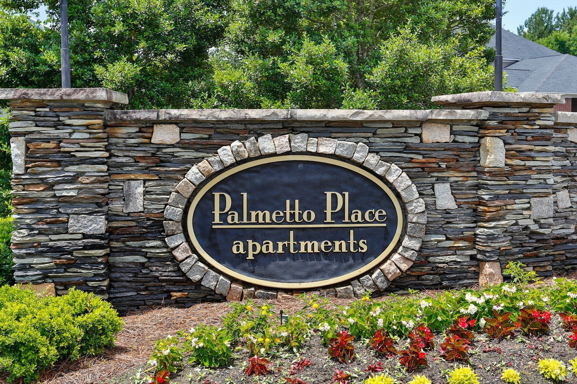 Sign for Palmetto Place Apartments made of stacked stone, with the name in gold lettering.