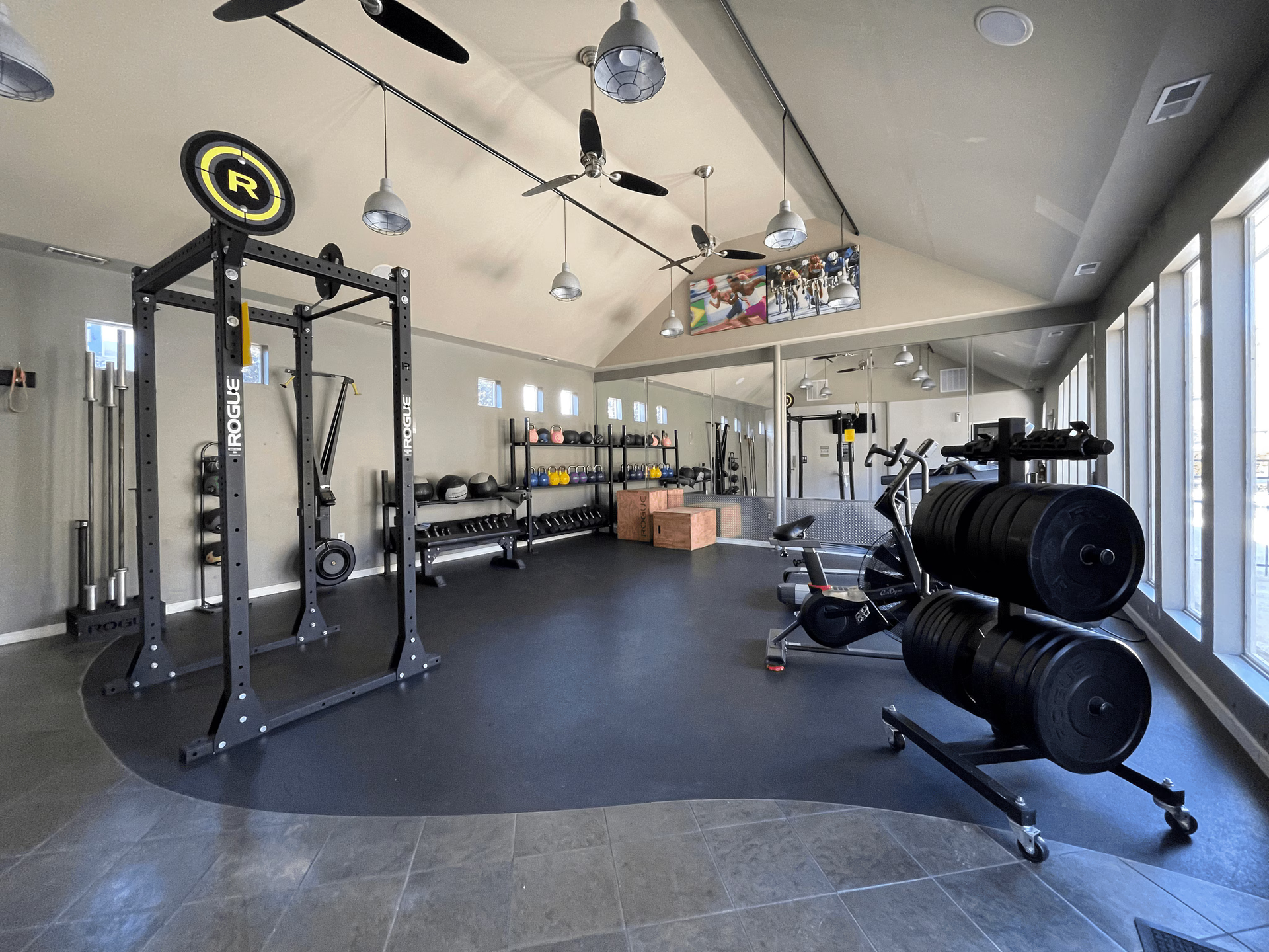 Home gym with weight rack, weights, exercise equipment, and large windows.