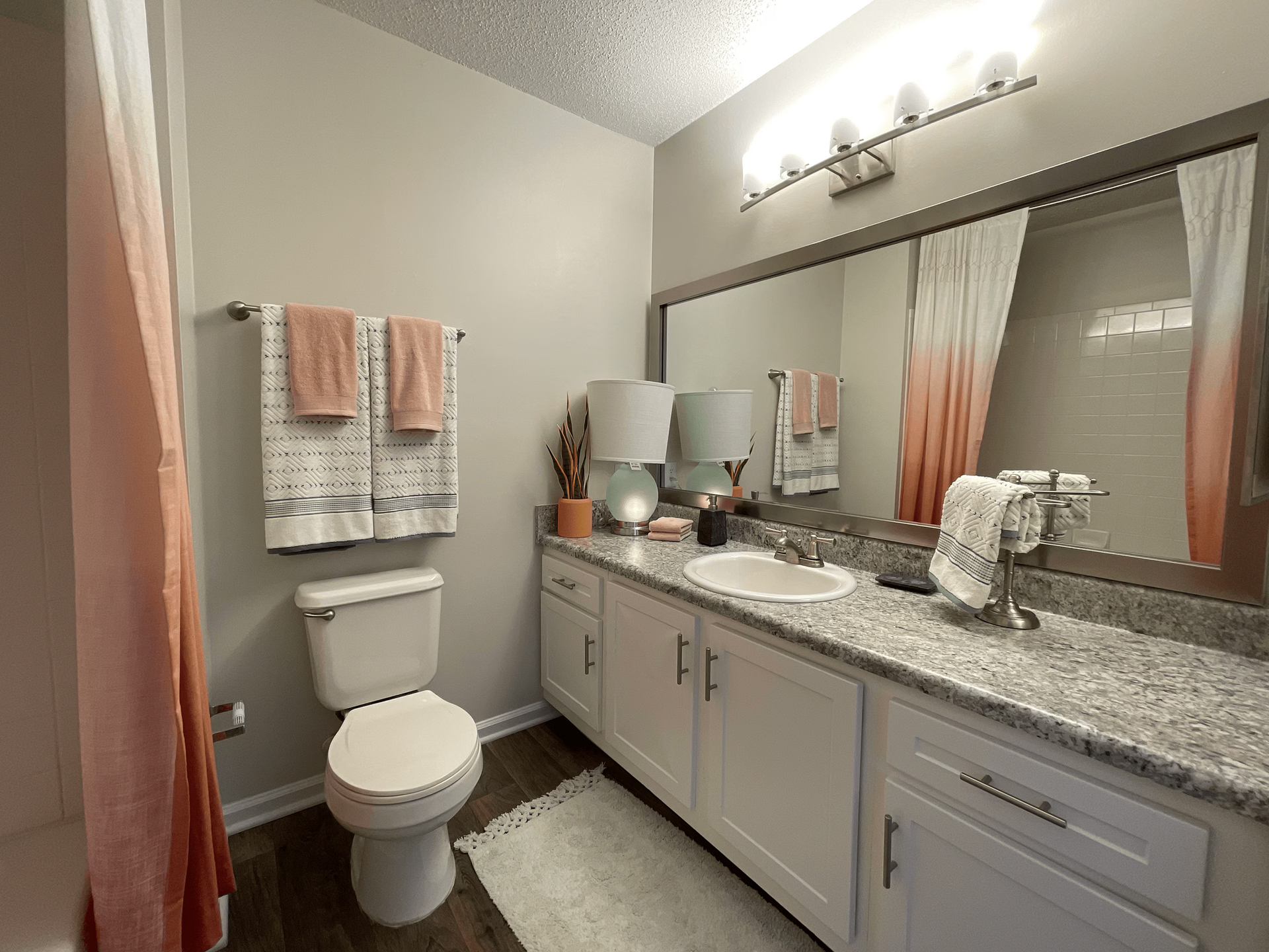Bathroom with white vanity, toilet, and sink; peach and white decor.