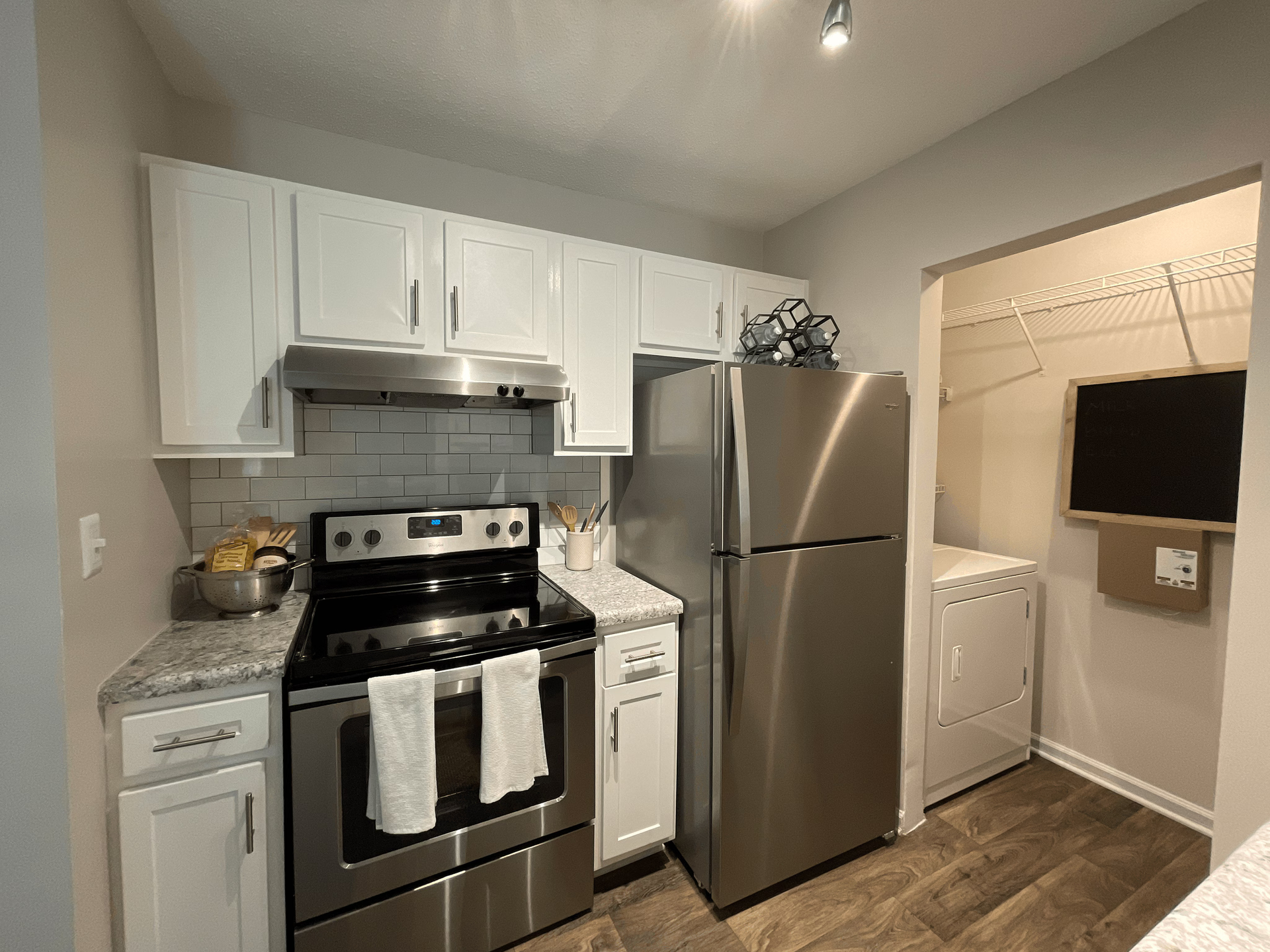 Kitchen with stainless steel appliances, white cabinets, and a washer/dryer.