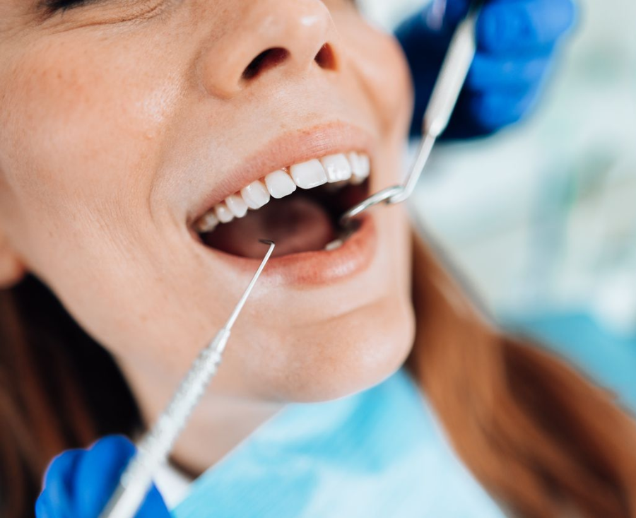 Woman at dentist; mouth open, tools in use.