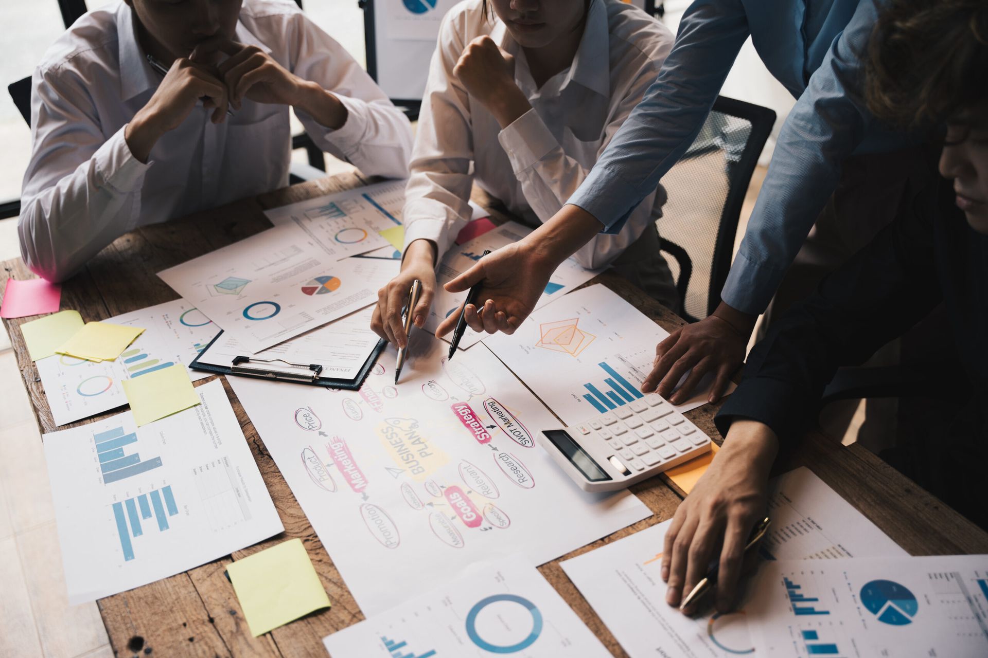 A group of people are sitting around a table looking at charts and graphs.