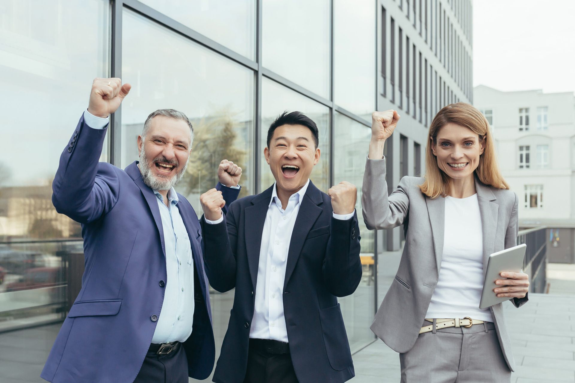 A group of business people are standing next to each other with their hands in the air.