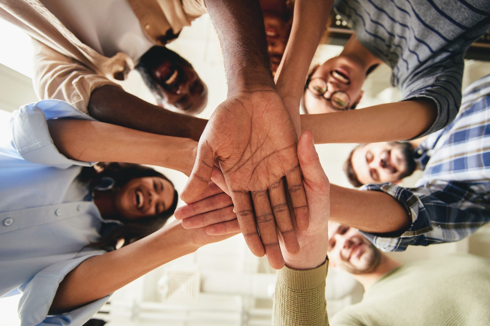 A group of people are putting their hands together in a circle.