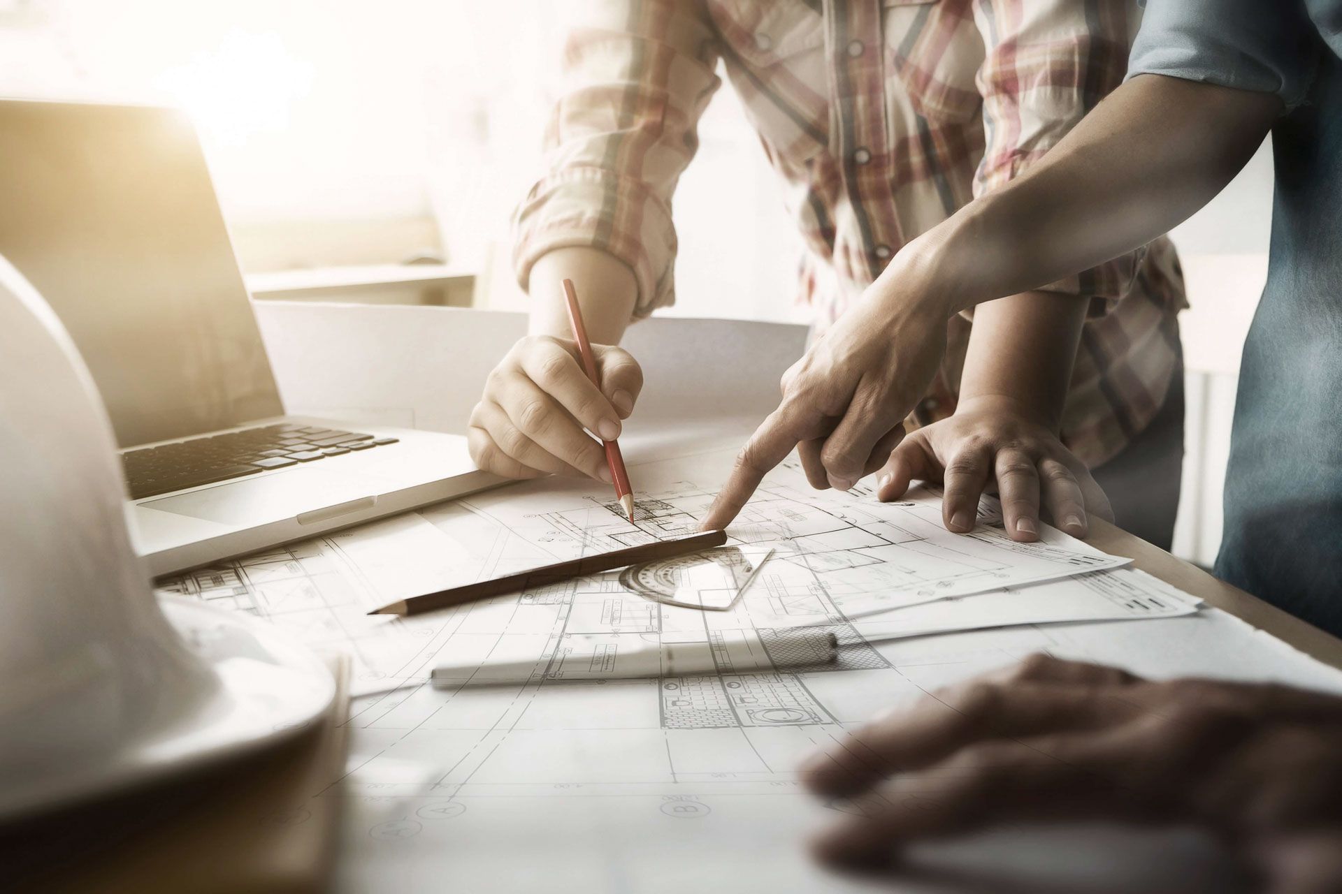 A group of people are sitting at a table looking at a blueprint.