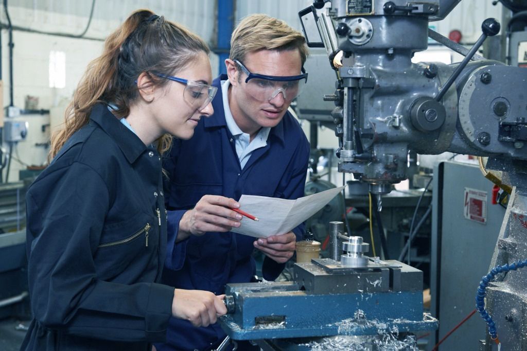 A man and a woman are working on a machine in a factory.