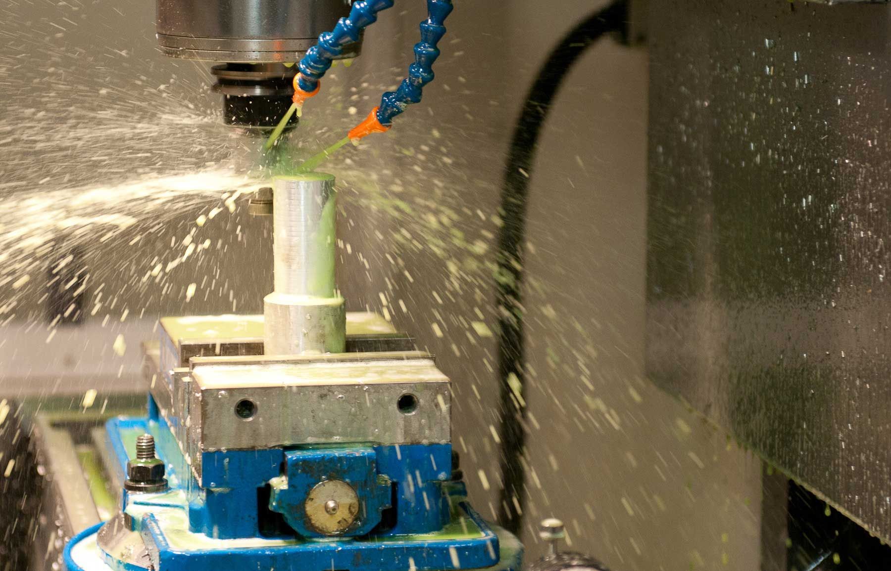 A machine is cutting a piece of metal with liquid coming out of it.