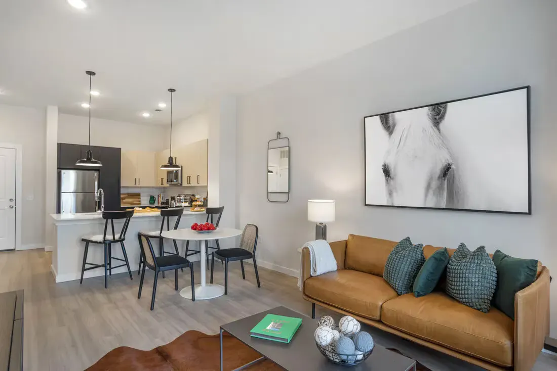 Open-concept living area with tan leather sofa, round dining table, and modern kitchen island.