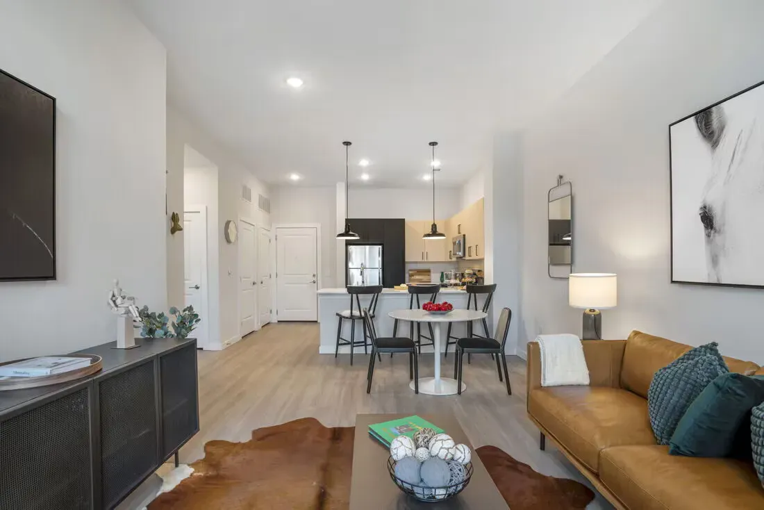 Open-concept living room and kitchen in a modern apartment with sofa, dining table, and island.