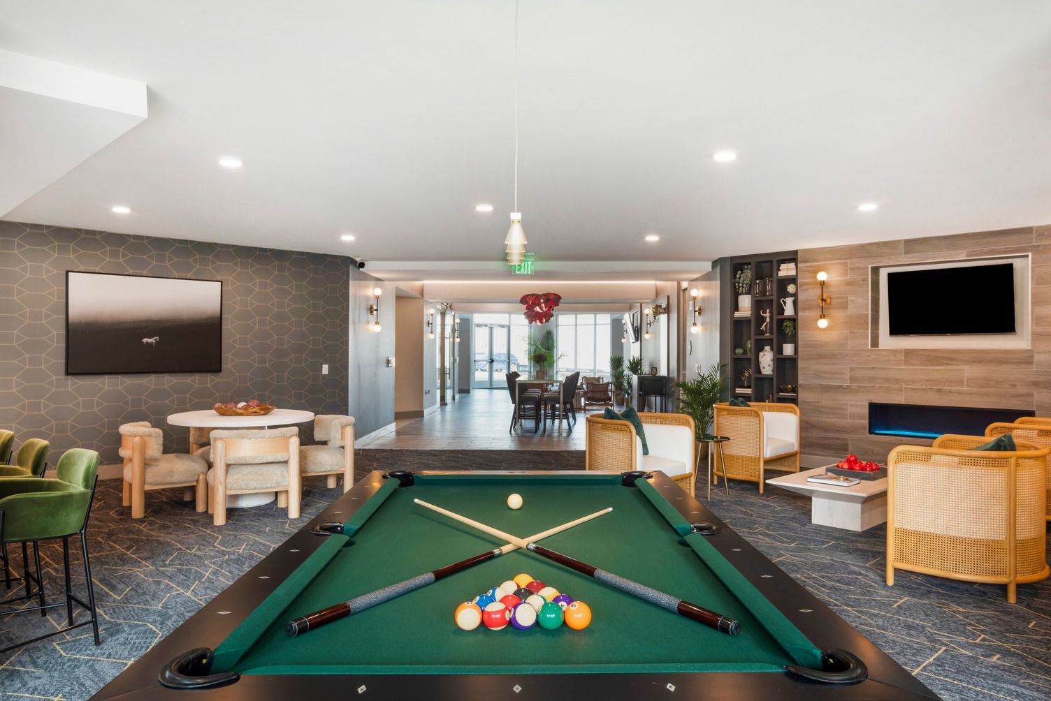 Interior community lounge with a billiards table, seating area, and a wall-mounted TV.