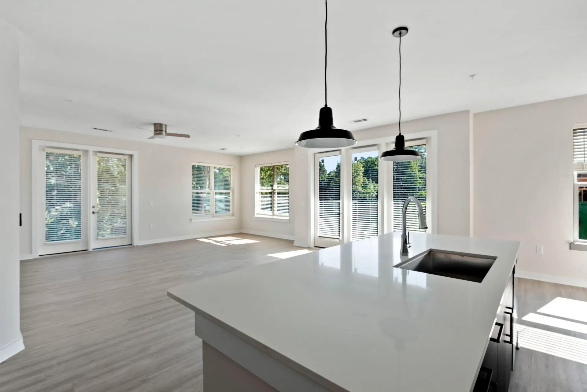 Bright open-concept kitchen and living space with a large island, pendant lights, and multiple windows.