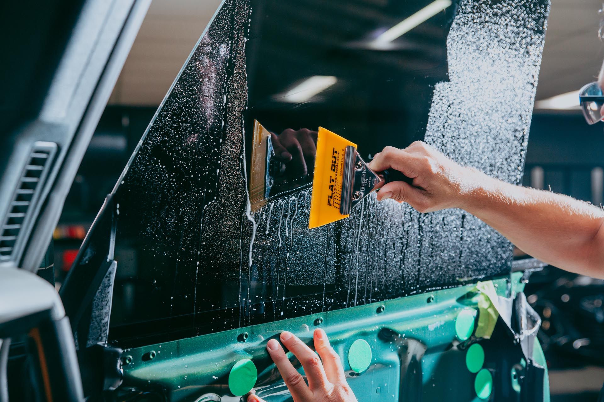 A person is applying window tinting to a car window.