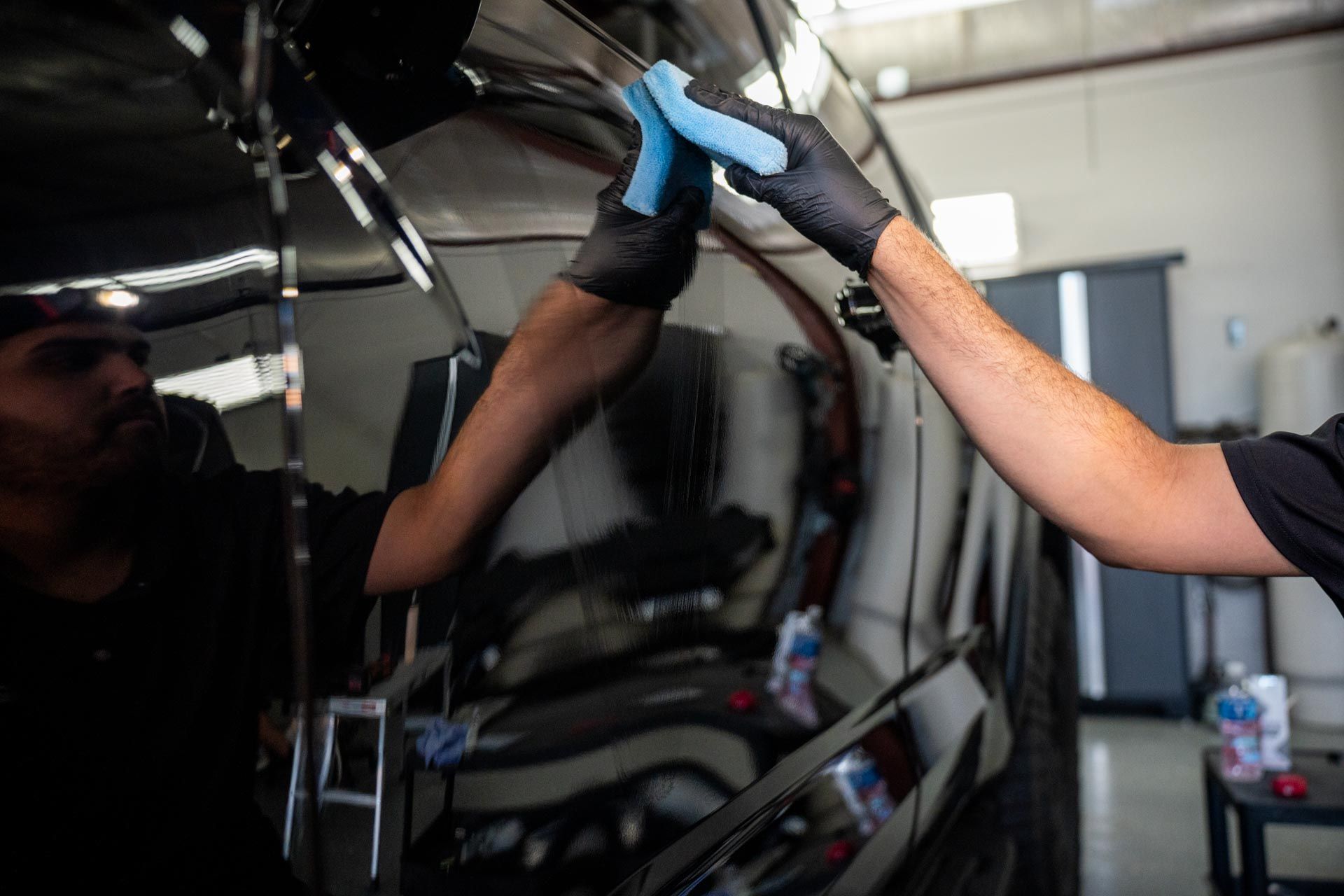 A man is cleaning a car with a cloth in a garage.