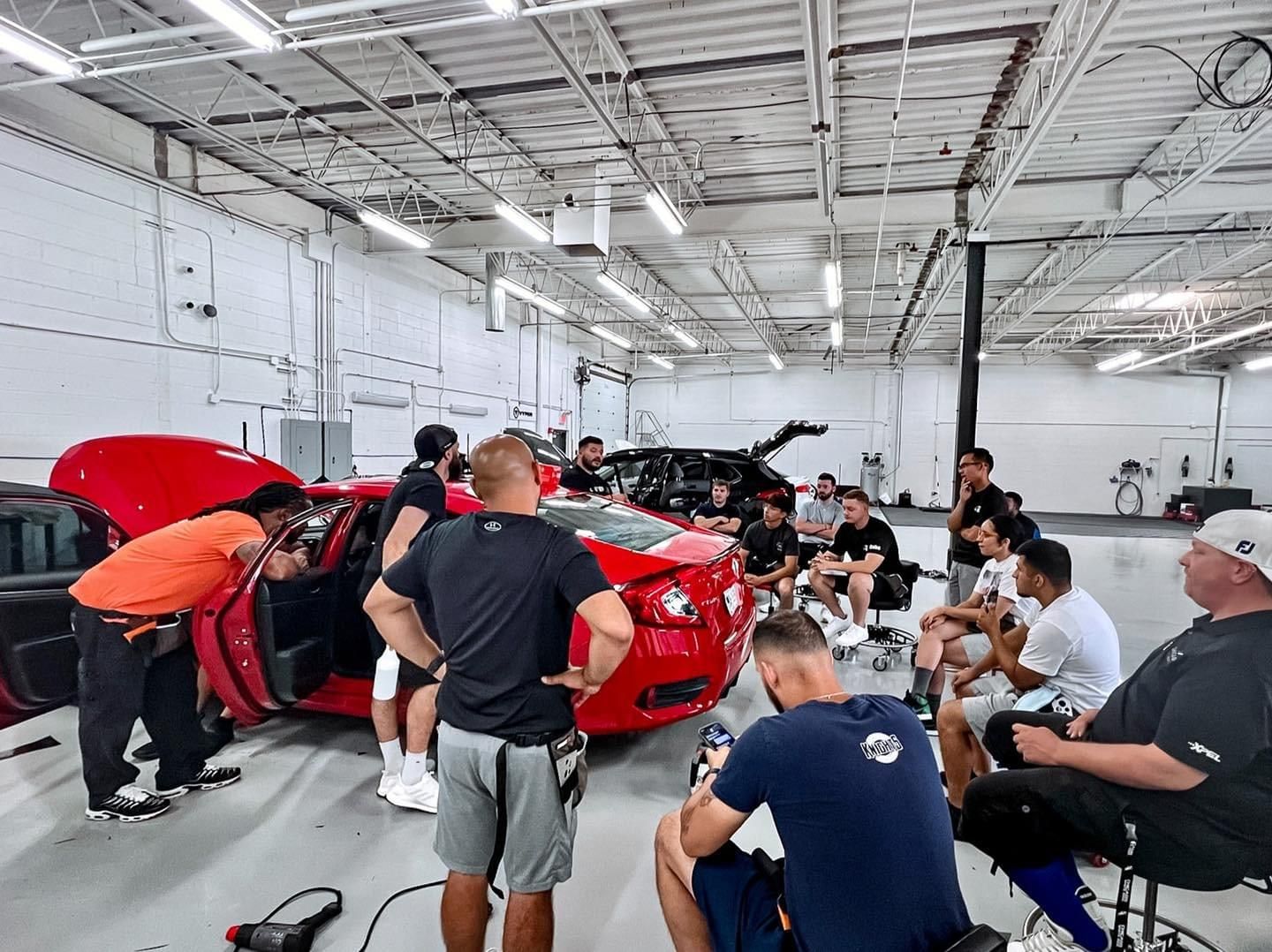 A group of men are working on a red sports car in a garage.