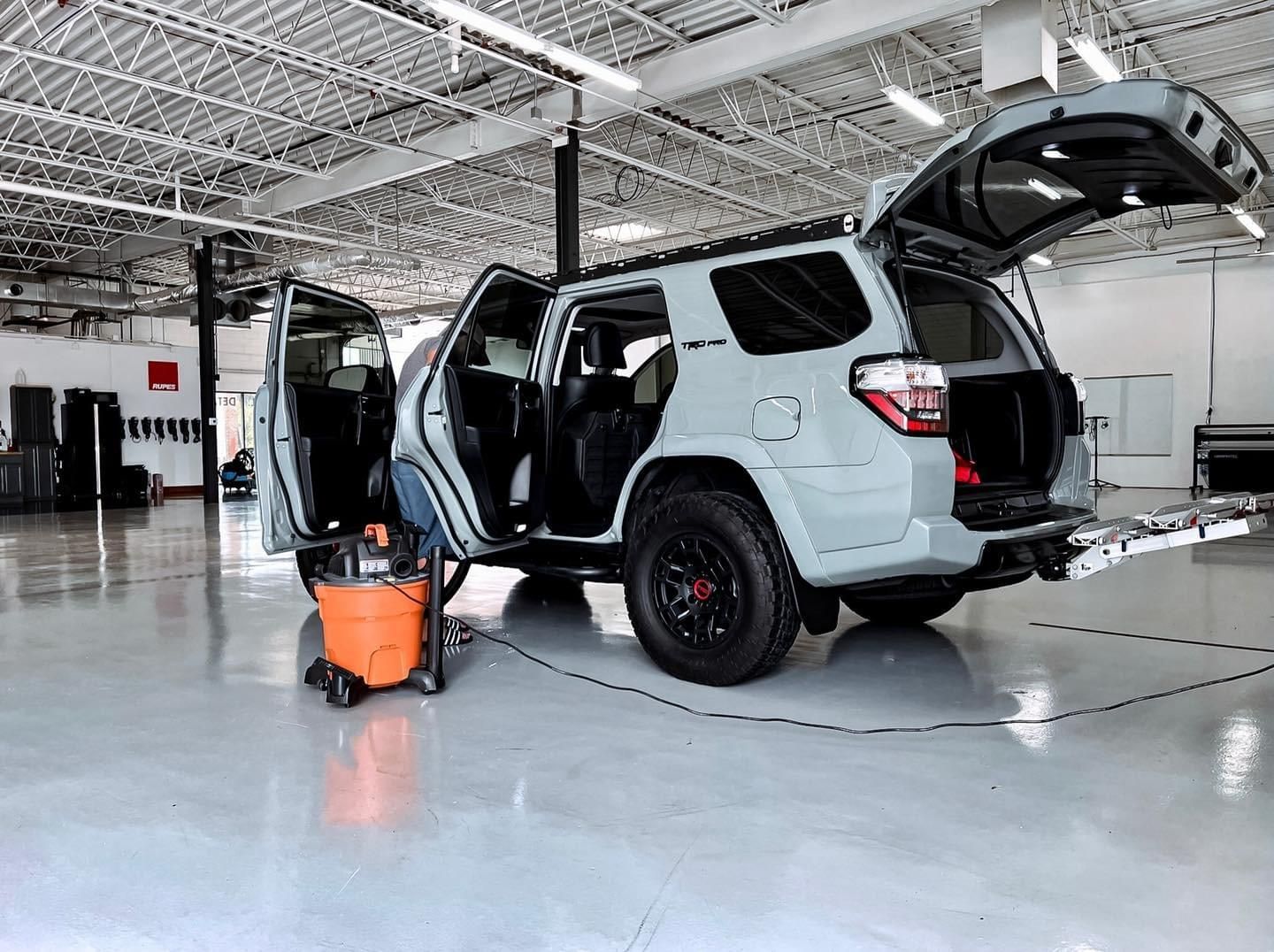 A white suv is parked in a garage with its trunk open.