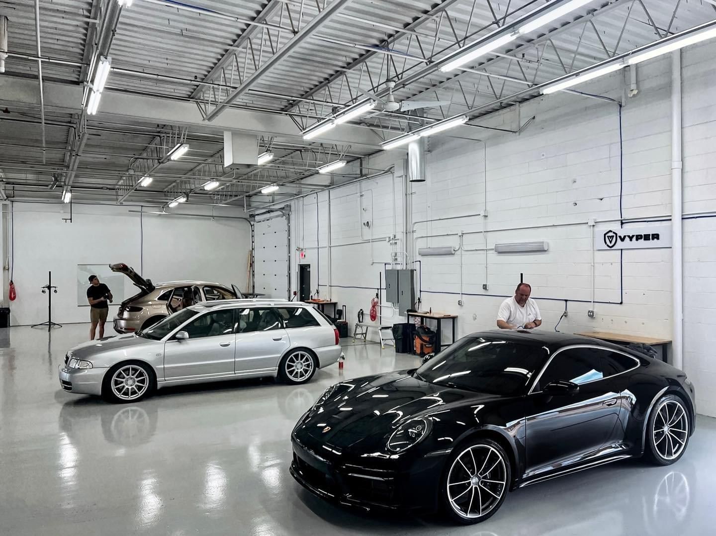 Two cars are parked in a garage next to each other.