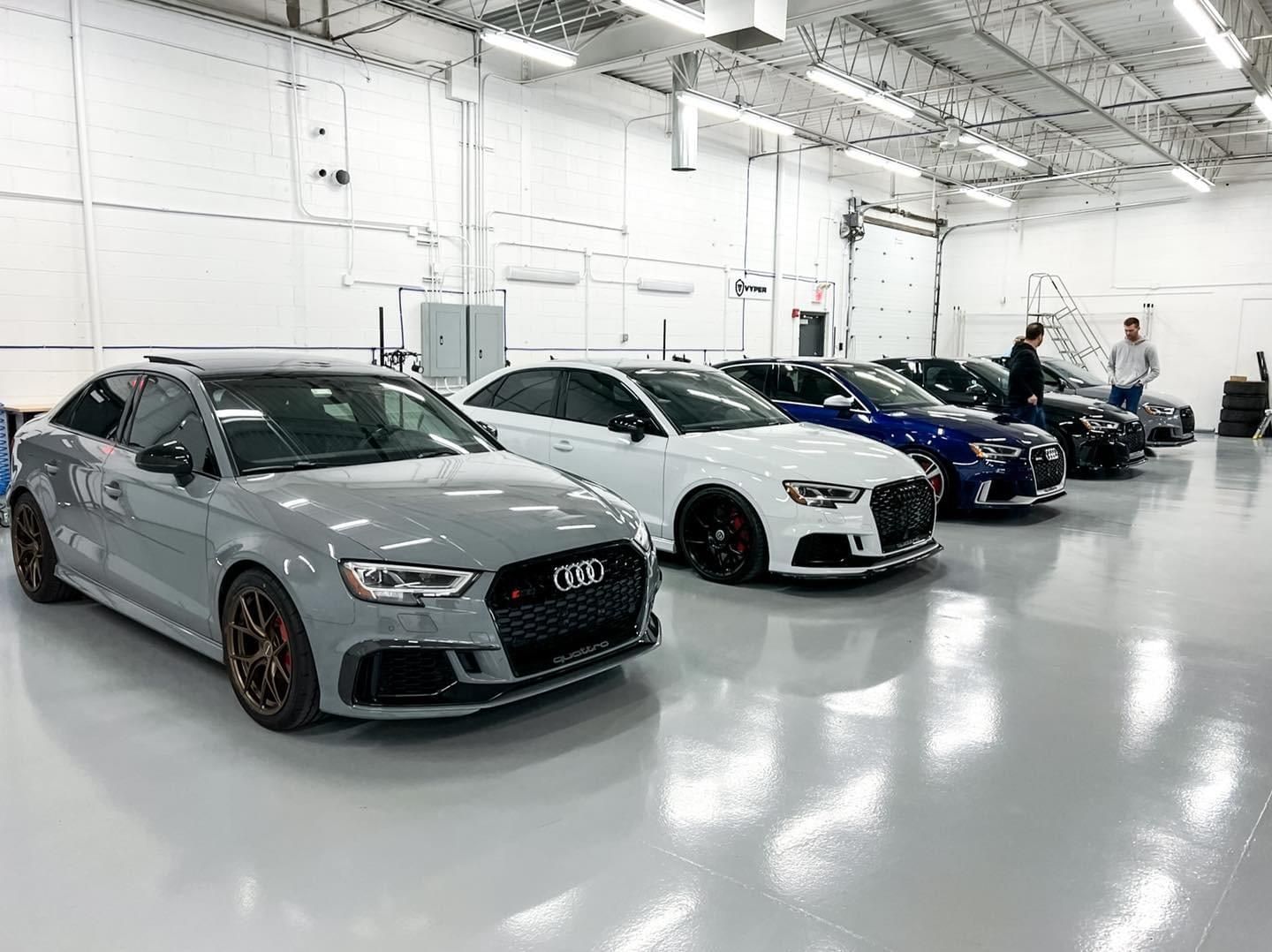 A row of cars are parked in a garage.