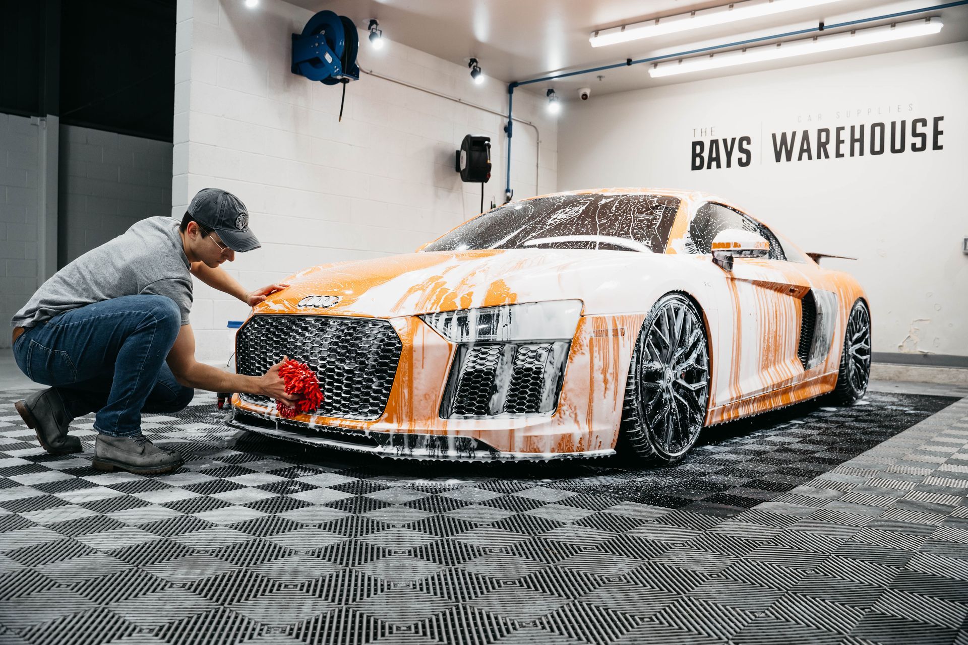 A man is washing a sports car in a garage.