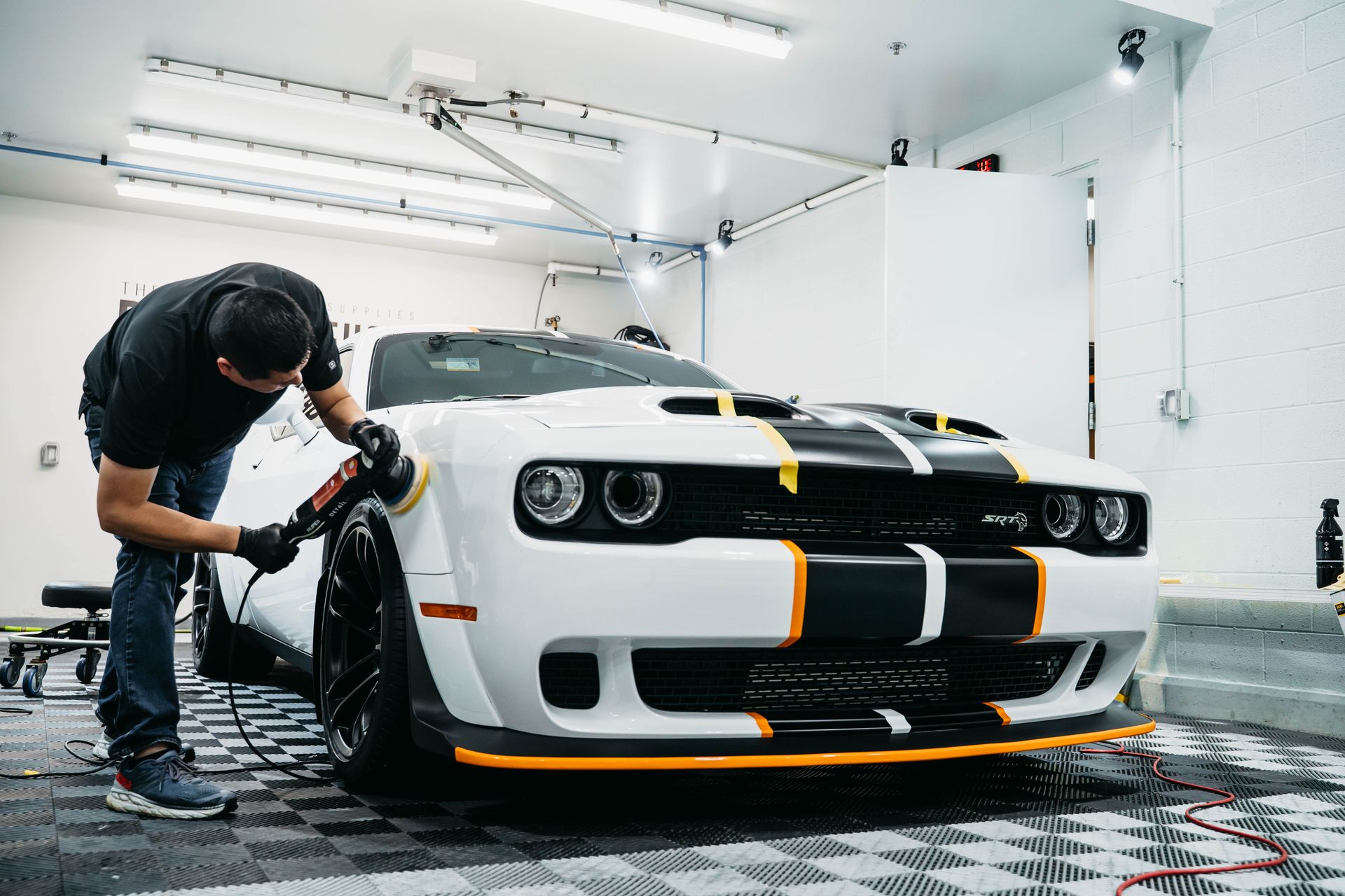 A man is polishing the hood of a car with a machine.