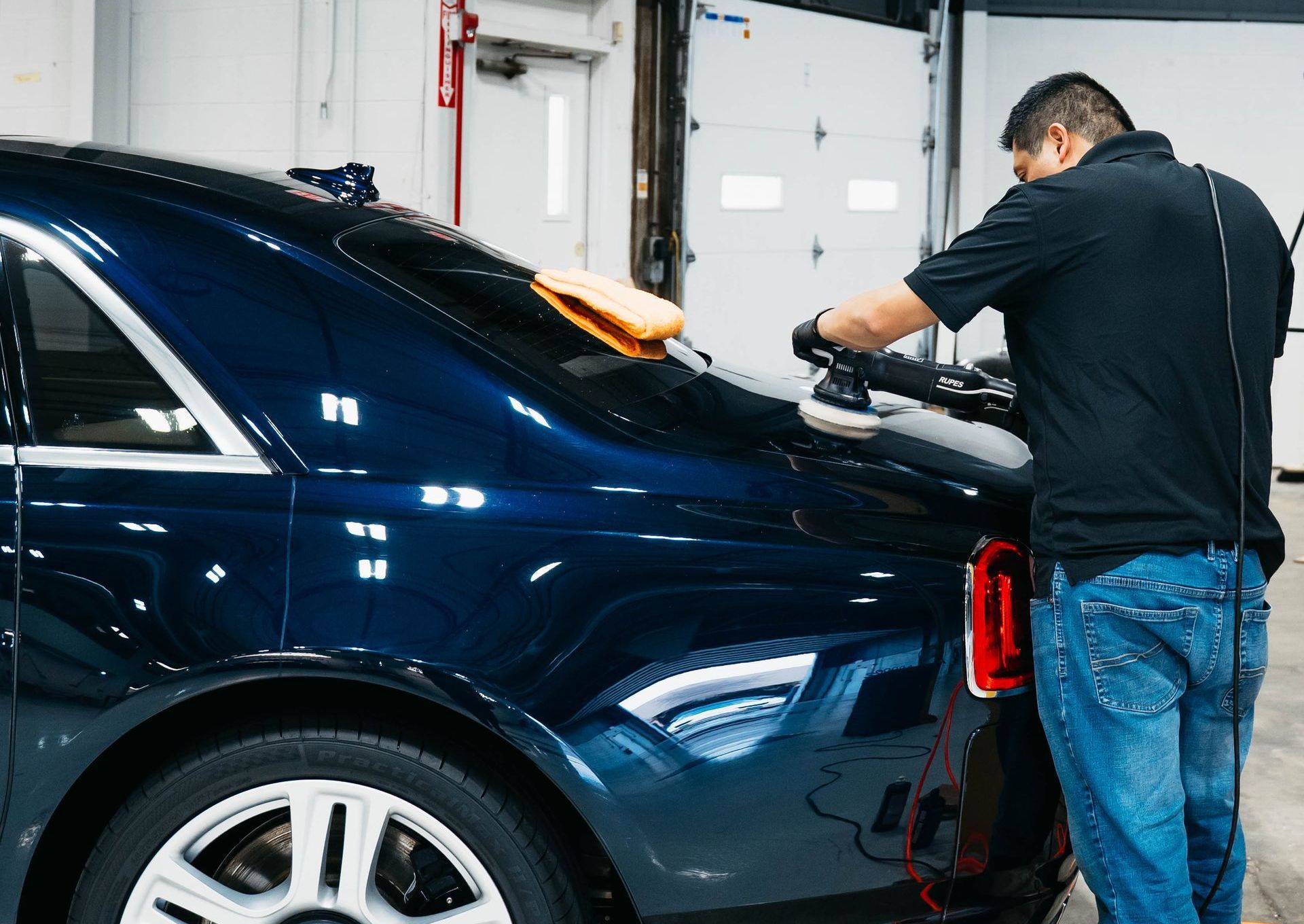 A man is polishing a car with a machine.