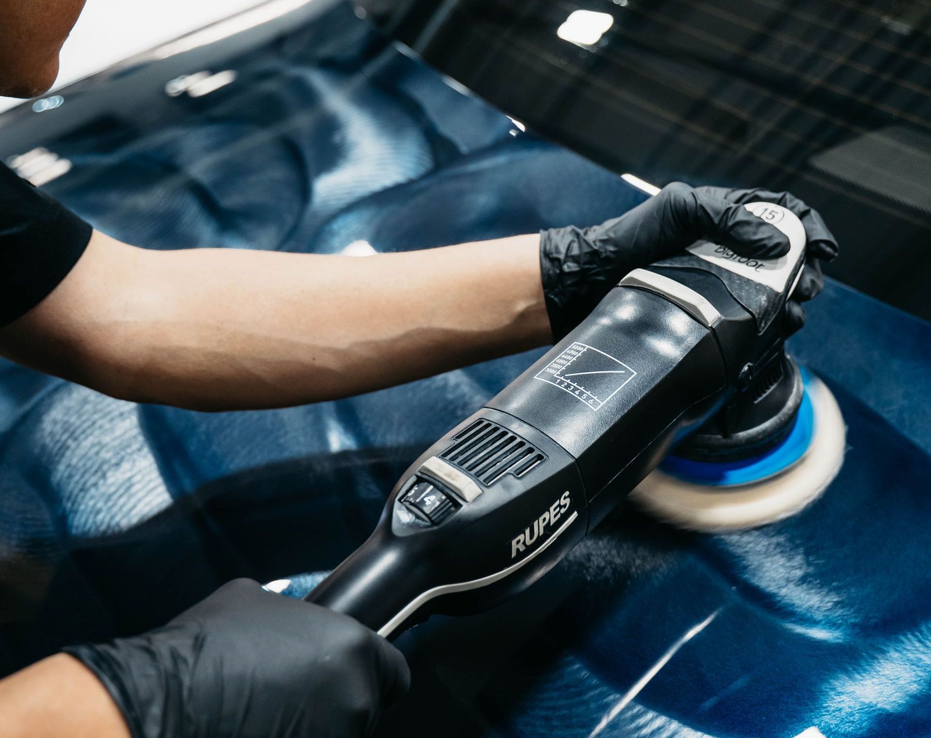 A man is polishing a white car with a machine.