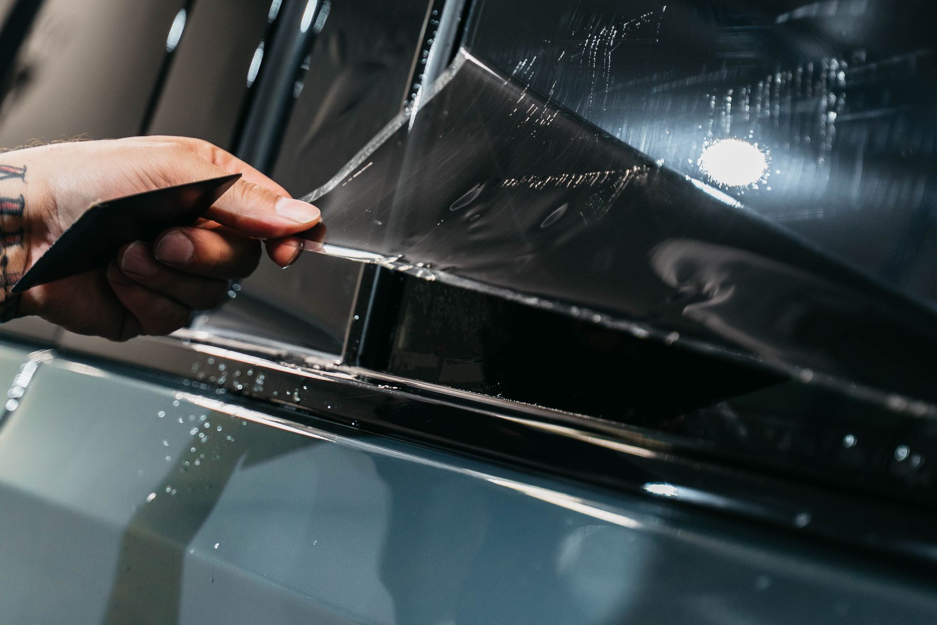 A person is installing window tinting on a car window.