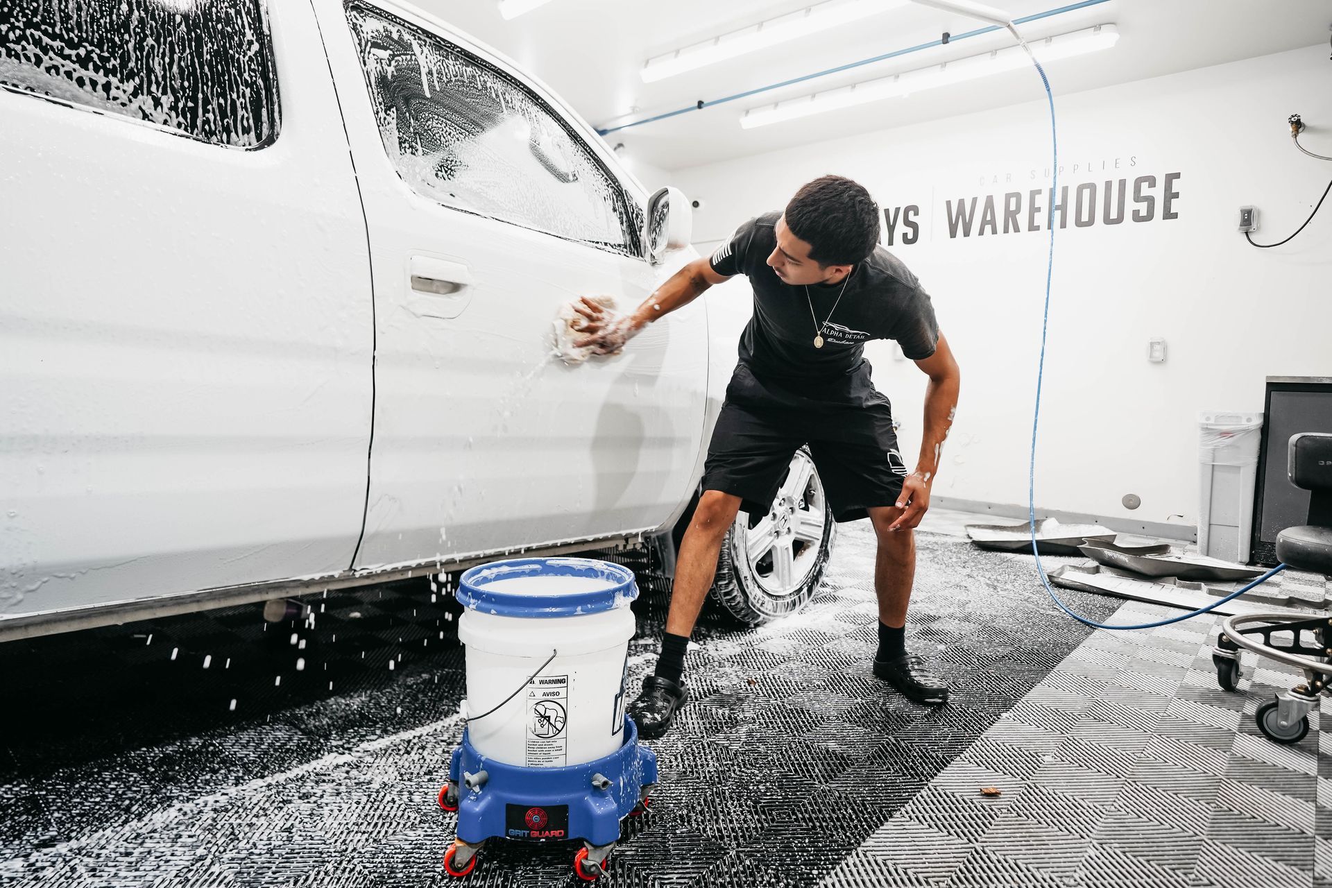 A man is washing a white truck in a garage.