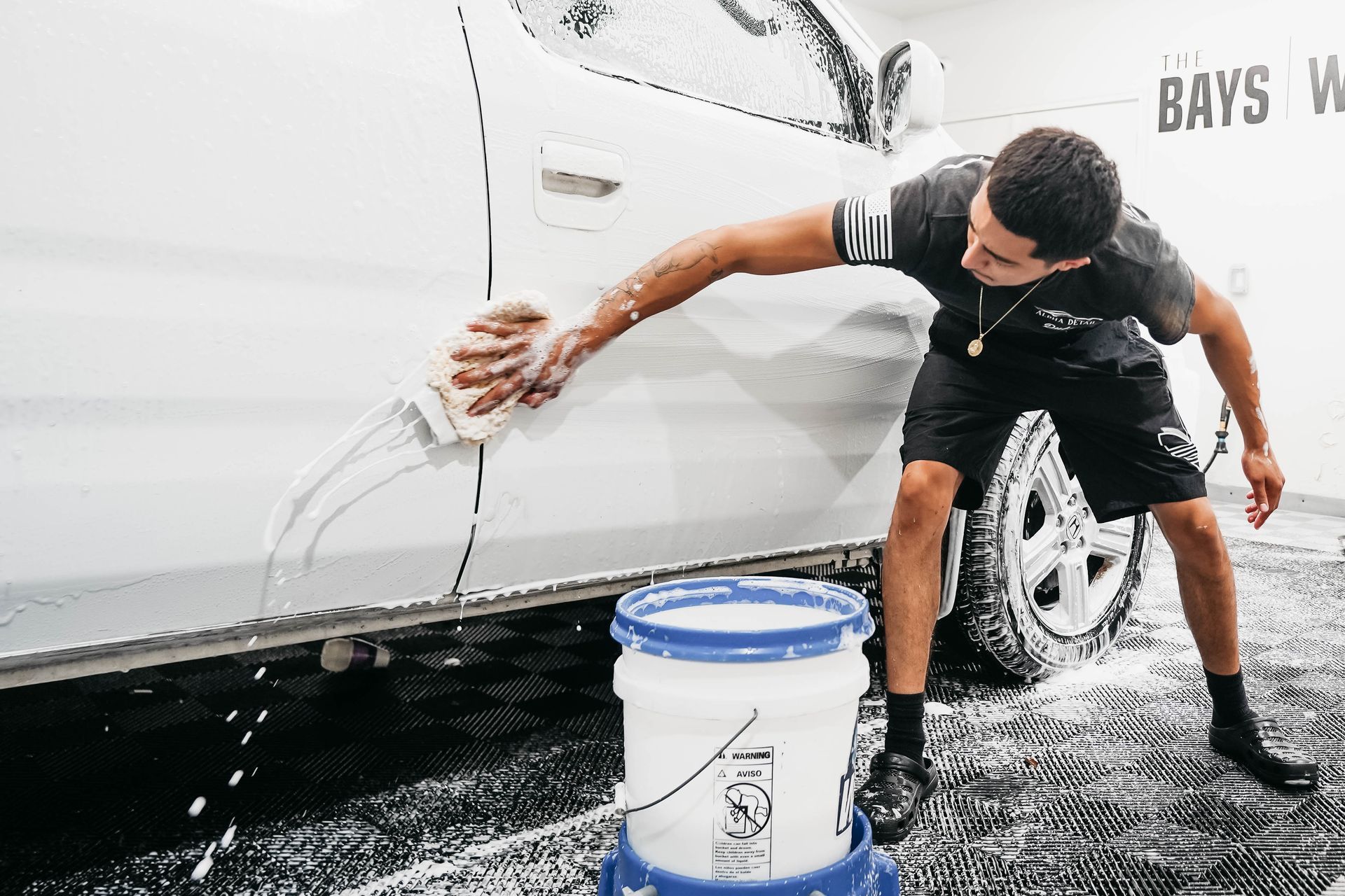 A man is washing a white car in a car wash.