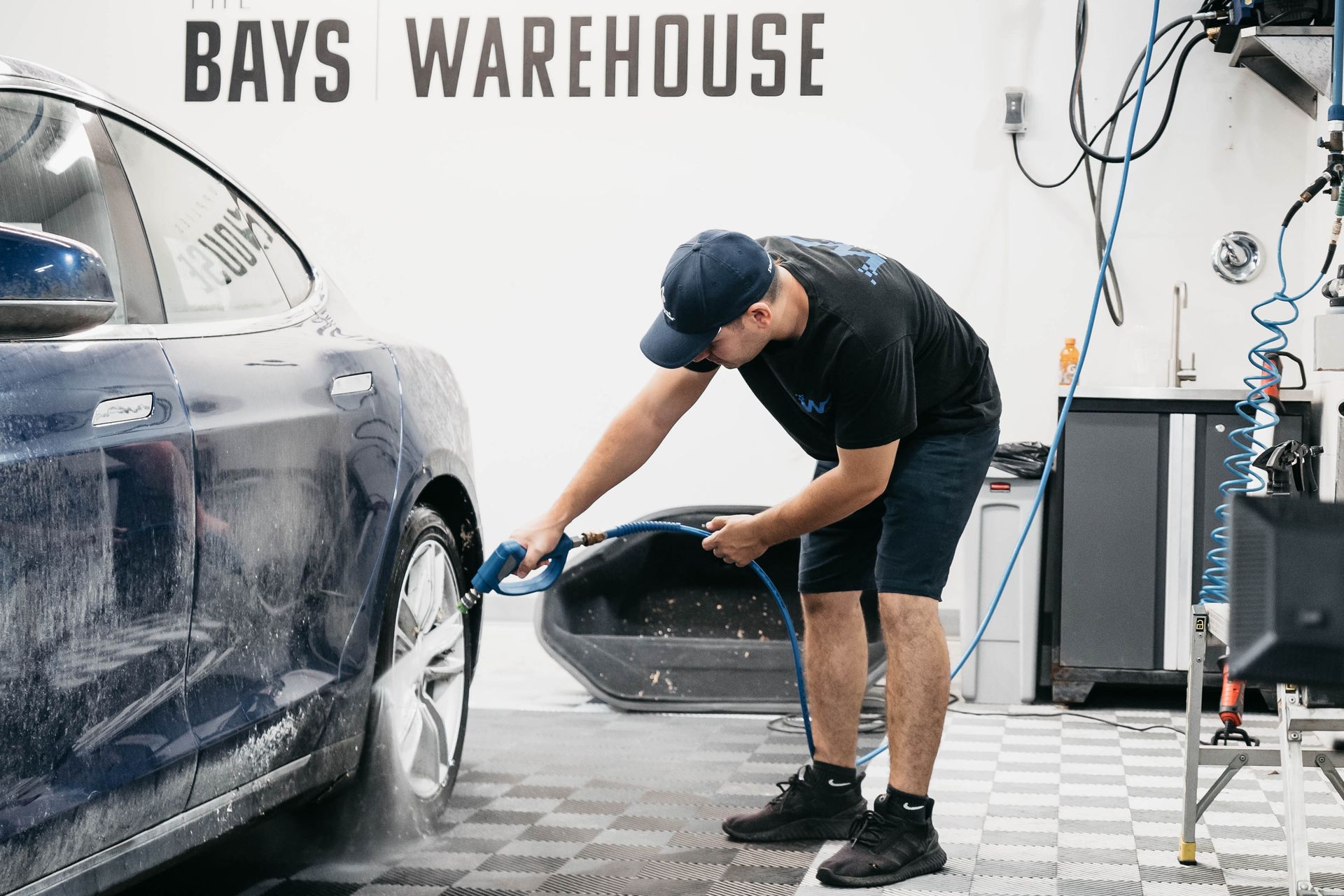 A man is washing a car in a garage.