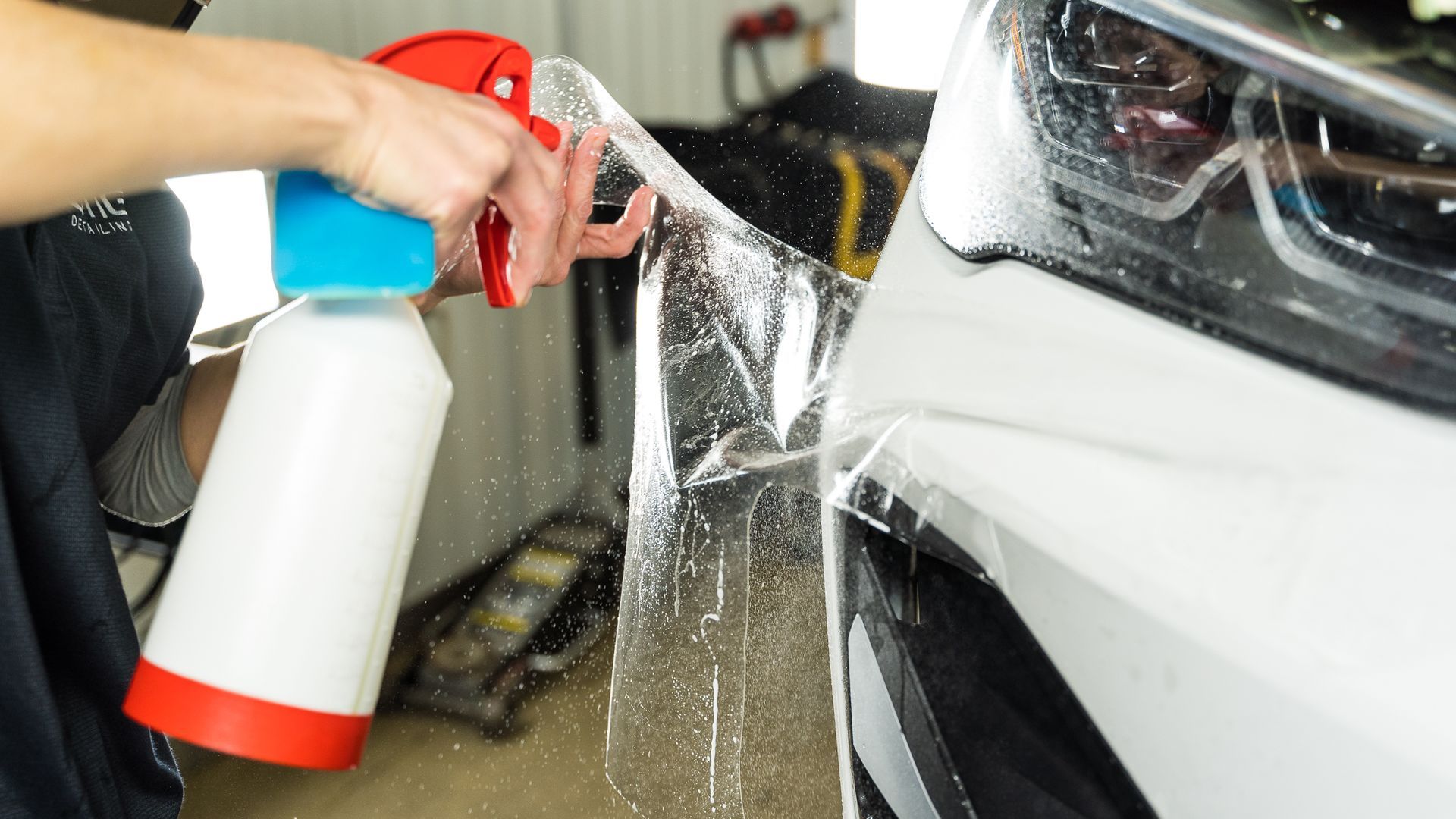 A person is spraying a car with a spray bottle.