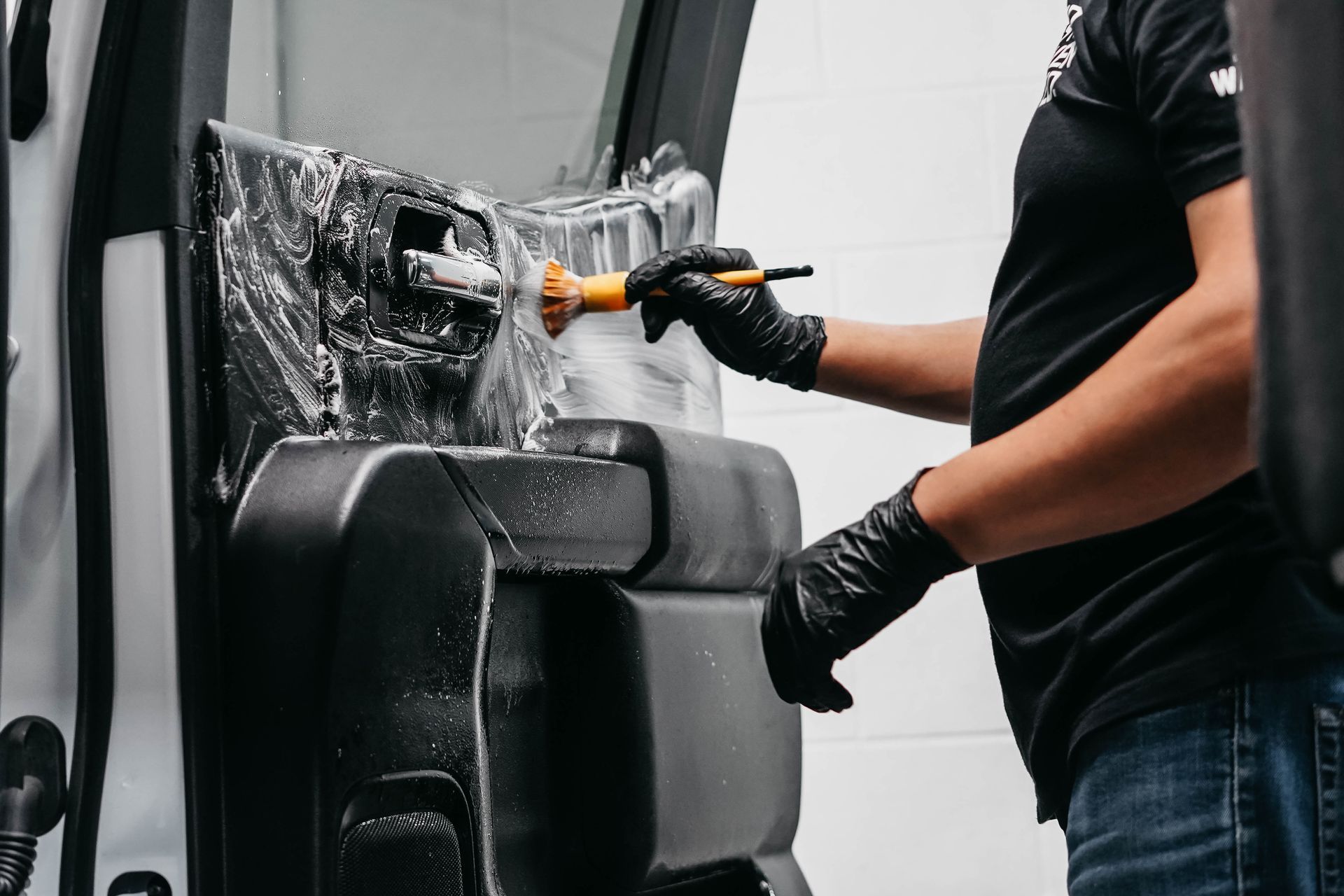 A man is cleaning the interior of a car with a brush.