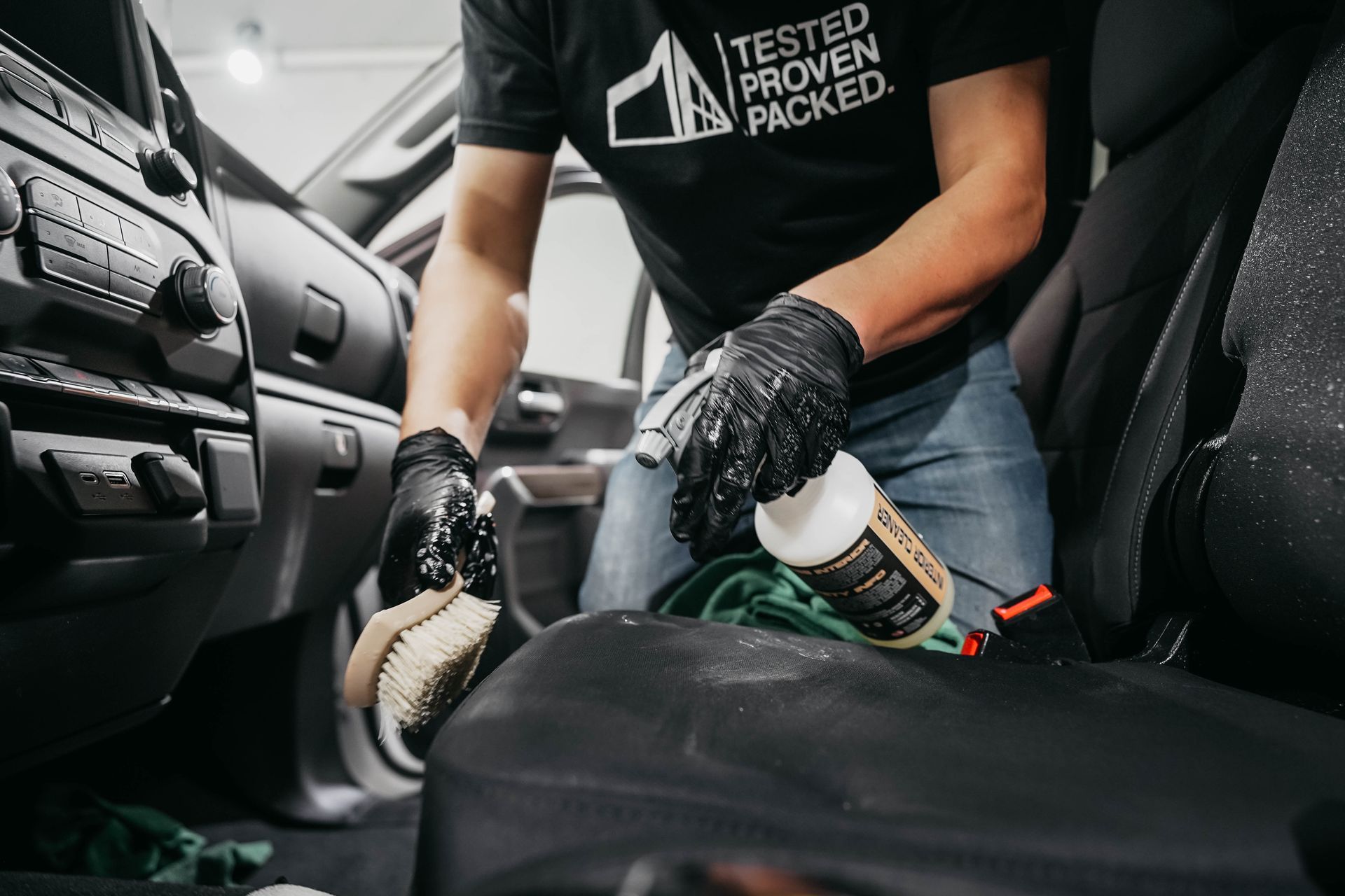 A man is cleaning the interior of a car with a brush.