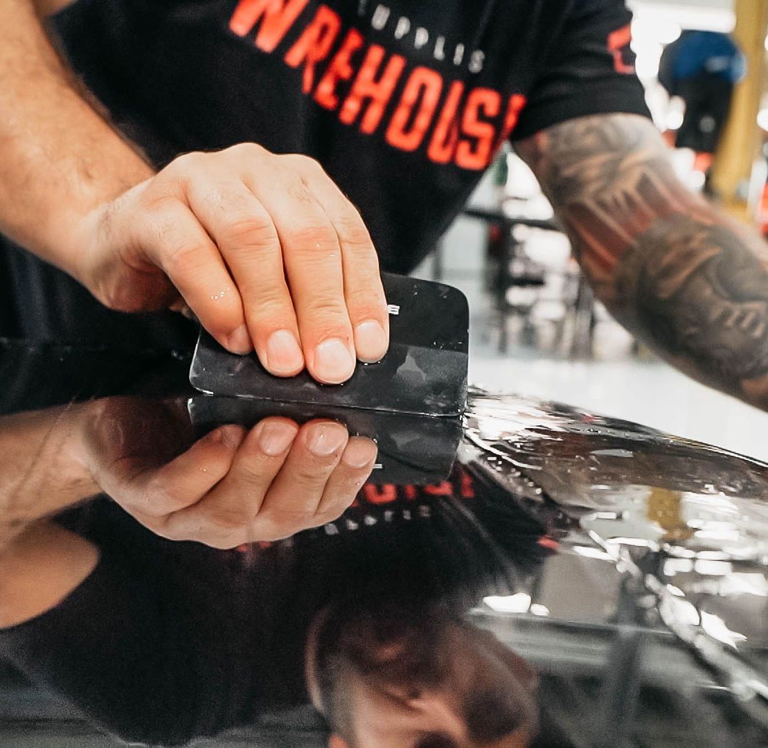 A man is cutting a piece of plastic with a pair of scissors.