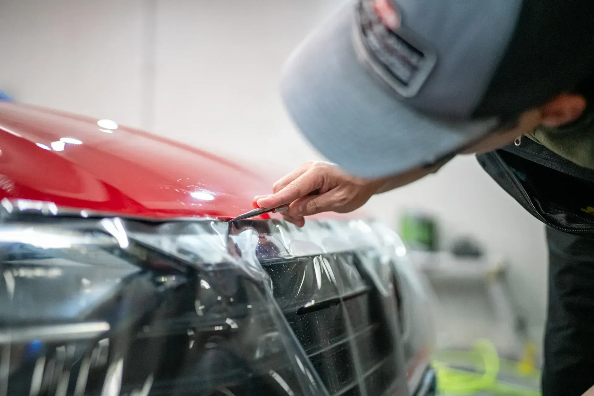 A man is wrapping a car with a piece of plastic.