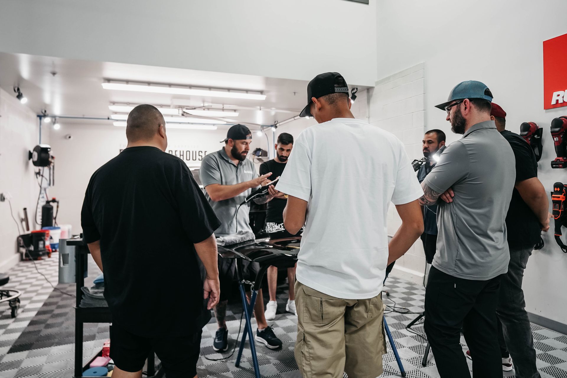 A group of men are standing around a table in a garage.