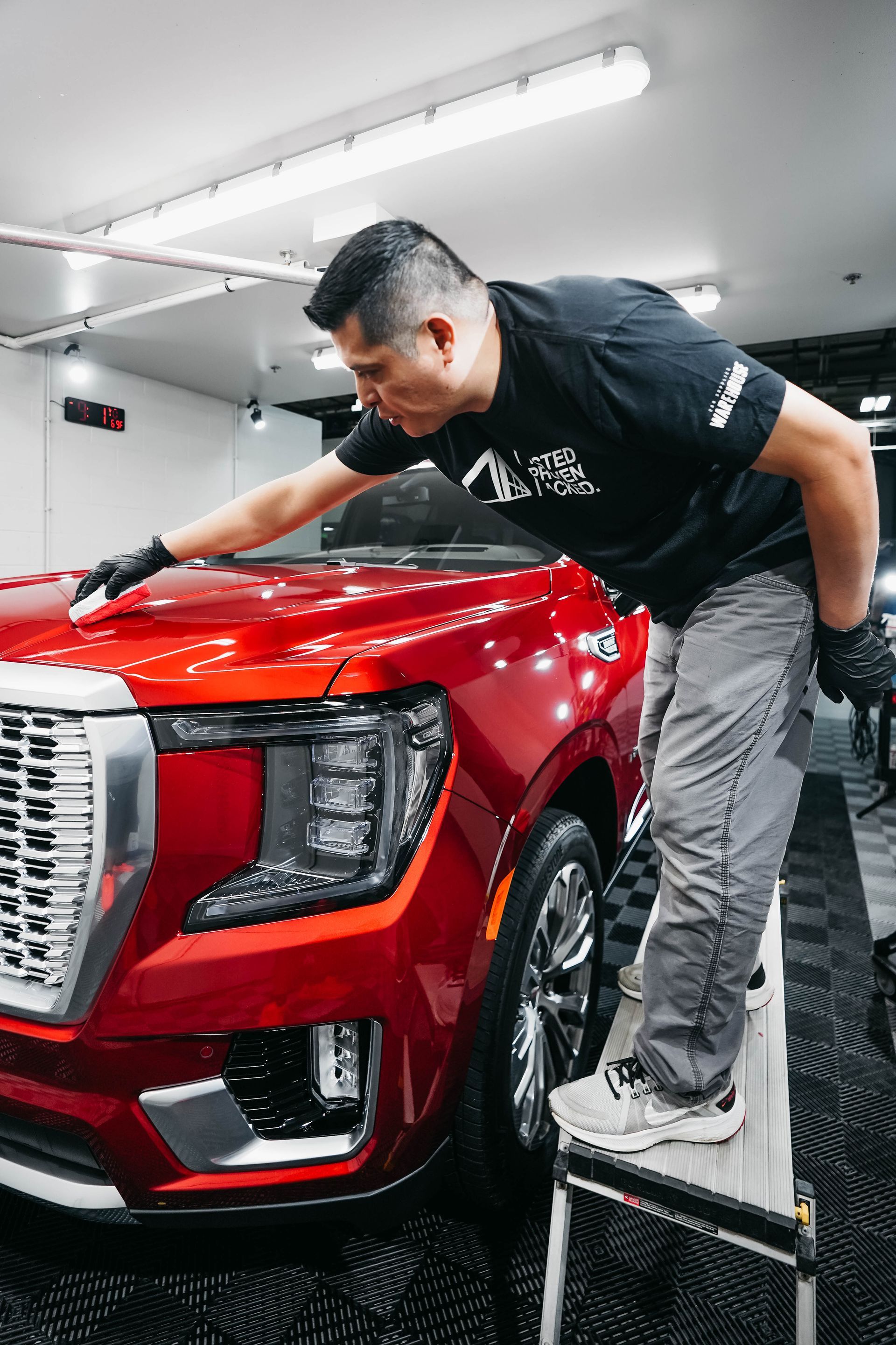 A man is washing a yellow car in a garage.