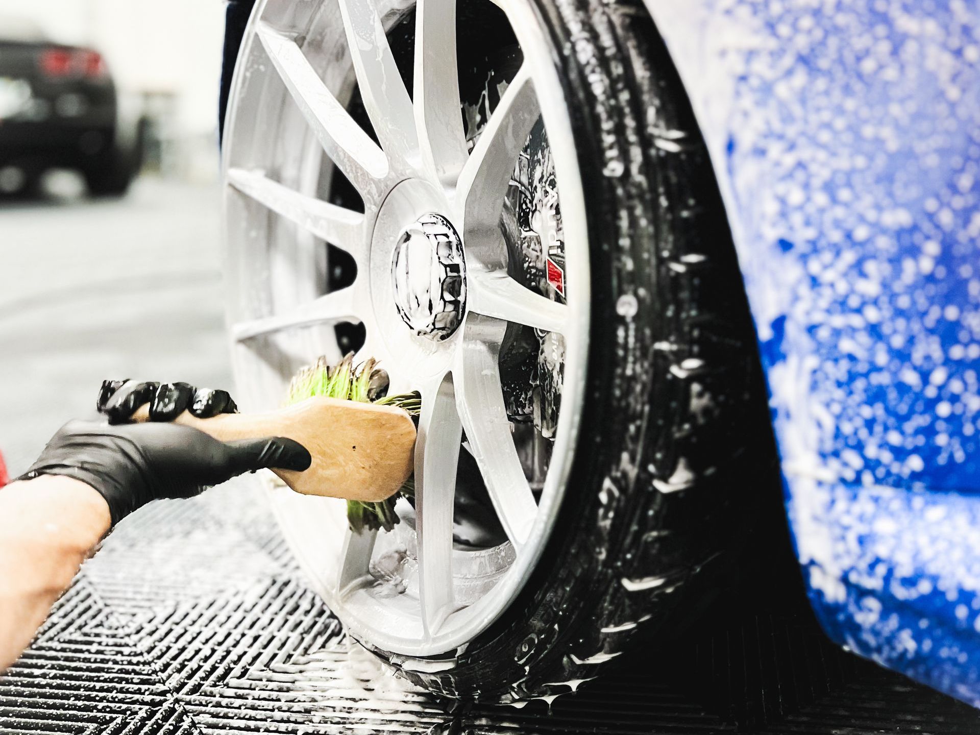 A person is cleaning a car wheel with a brush.