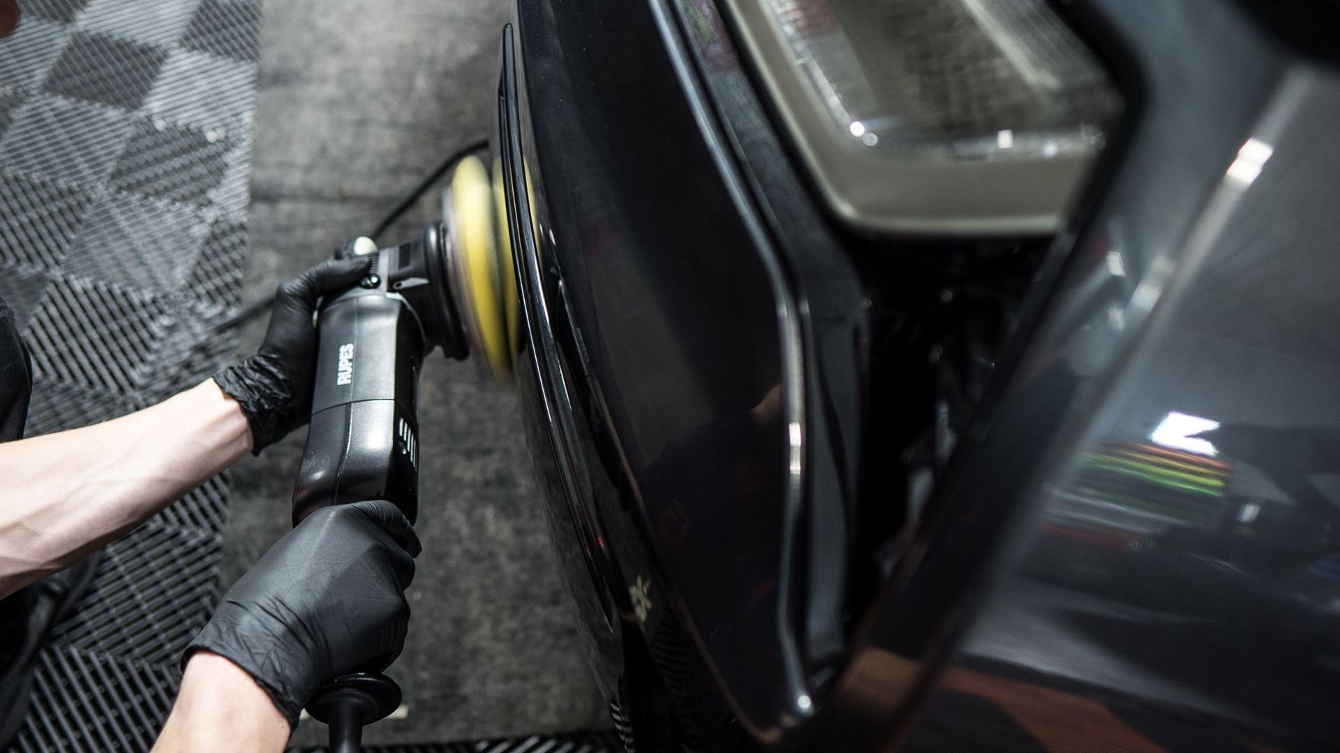 A person is polishing a car with a machine.