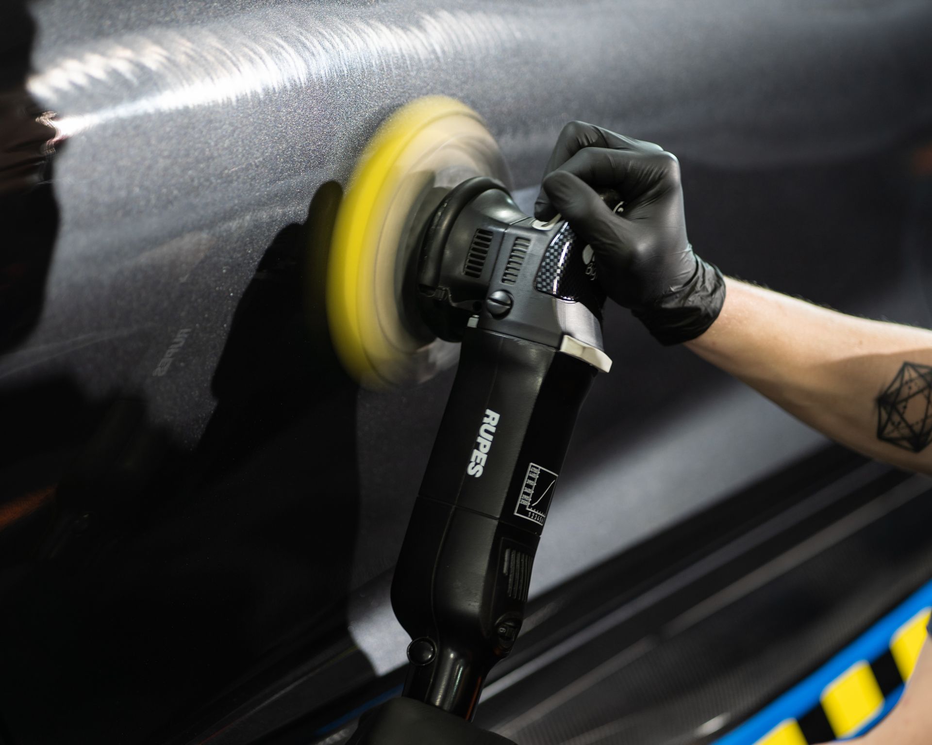 A person is polishing a car with a machine.