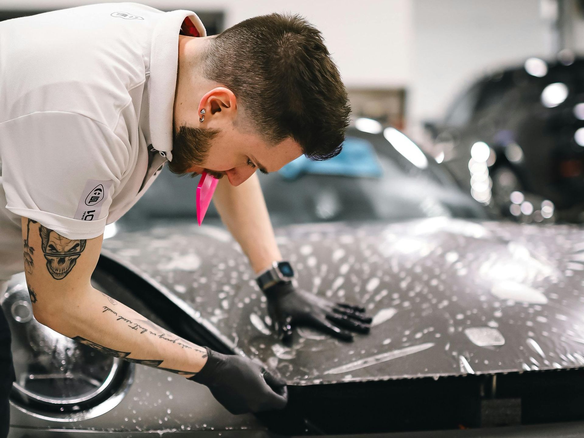 A man is working on the hood of a car.