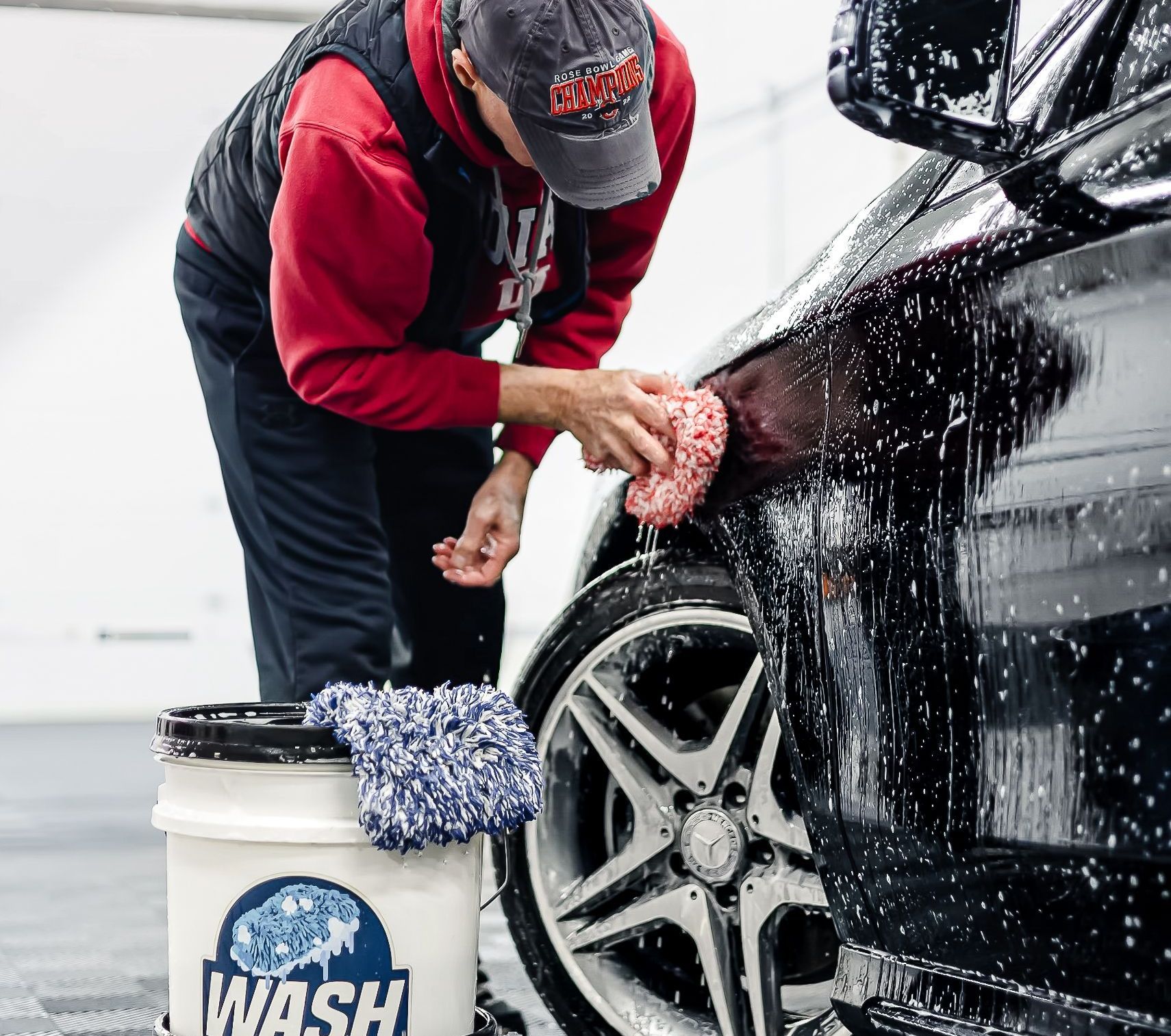A man with tattoos is cleaning a car with a cloth.
