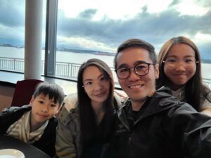 A man is taking a selfie with his family while sitting at a table.