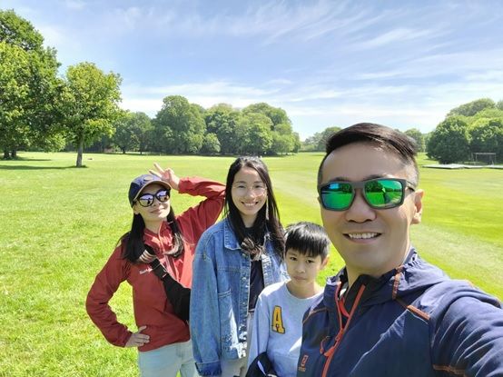 A man is taking a selfie with his family in a park.