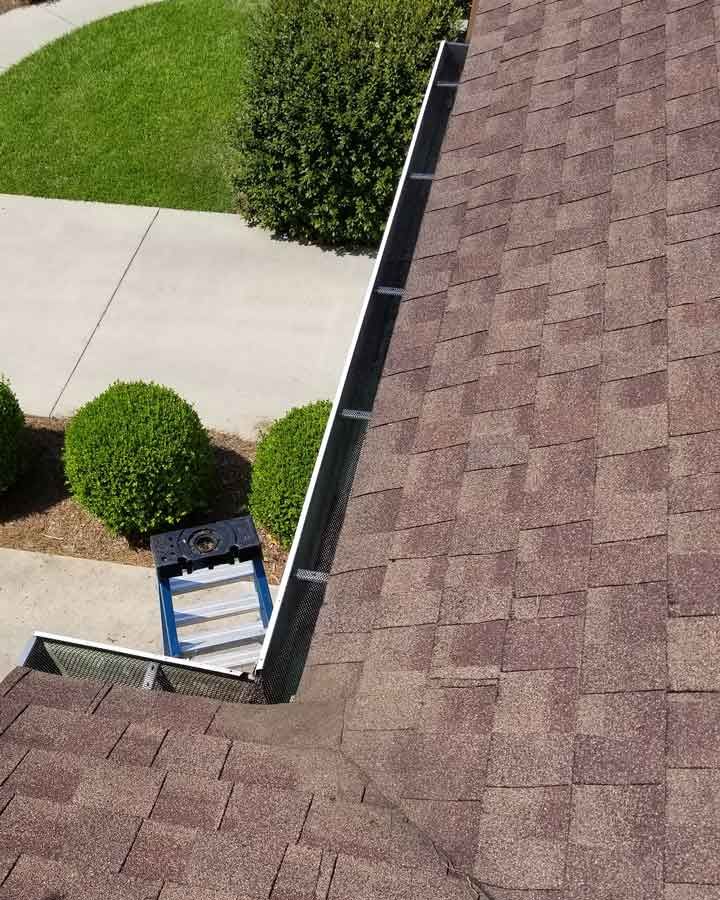 A ladder is sitting on top of a roof next to a gutter.