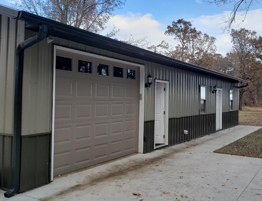 A large metal building with a garage door and two doors.