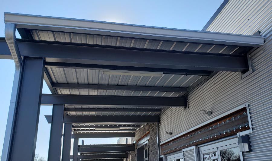 A covered walkway leading to a building with a metal roof.