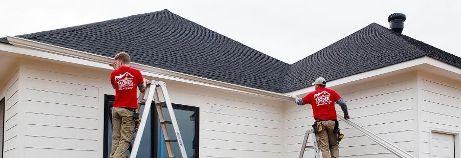 Two men are working on the roof of a house.