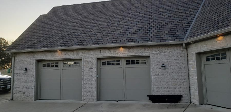There are three garage doors on the side of a house.