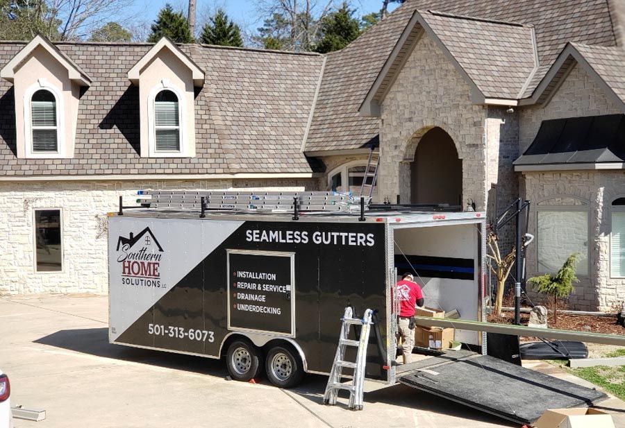 A seamless gutters trailer is parked in front of a house.