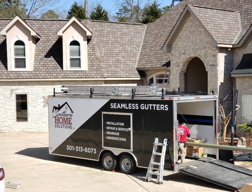 A seamless gutters trailer is parked in front of a house.